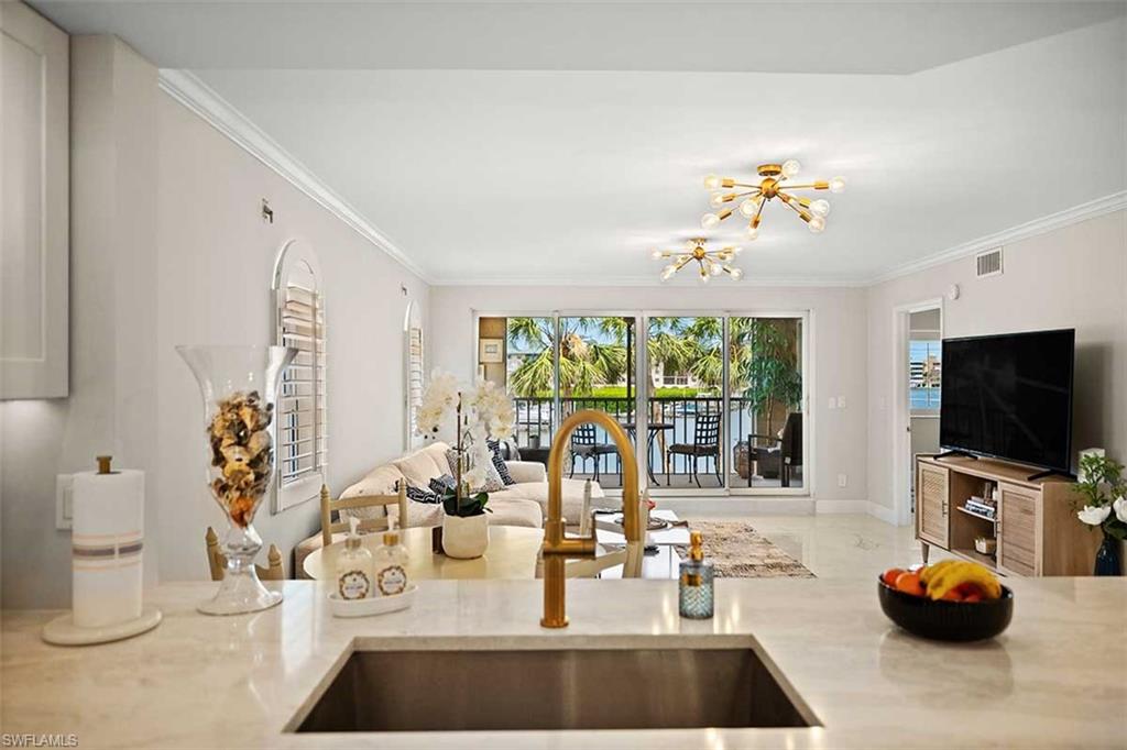 Kitchen counter with an undermount sink and brass-finish faucet, featuring a large pass-through opening to a living area
