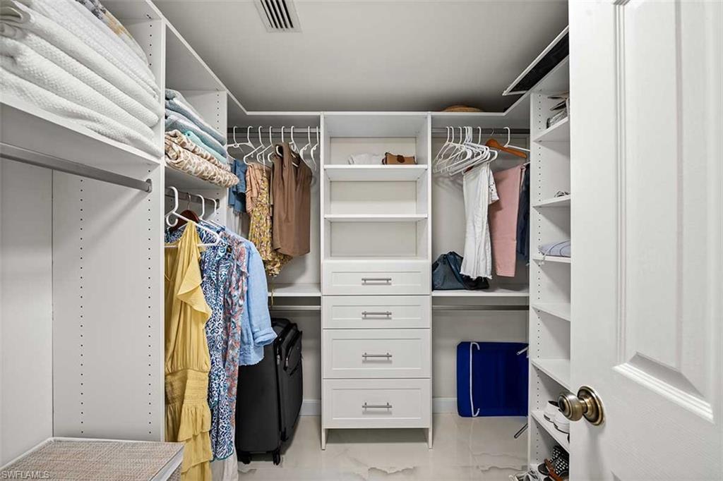 White custom closet system featuring multiple hanging rods, integrated shelving, and built-in drawers with brushed nickel hardware