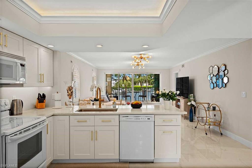 Contemporary kitchen featuring white cabinetry with gold-finish hardware, stainless steel appliances, and a built-in dishwasher