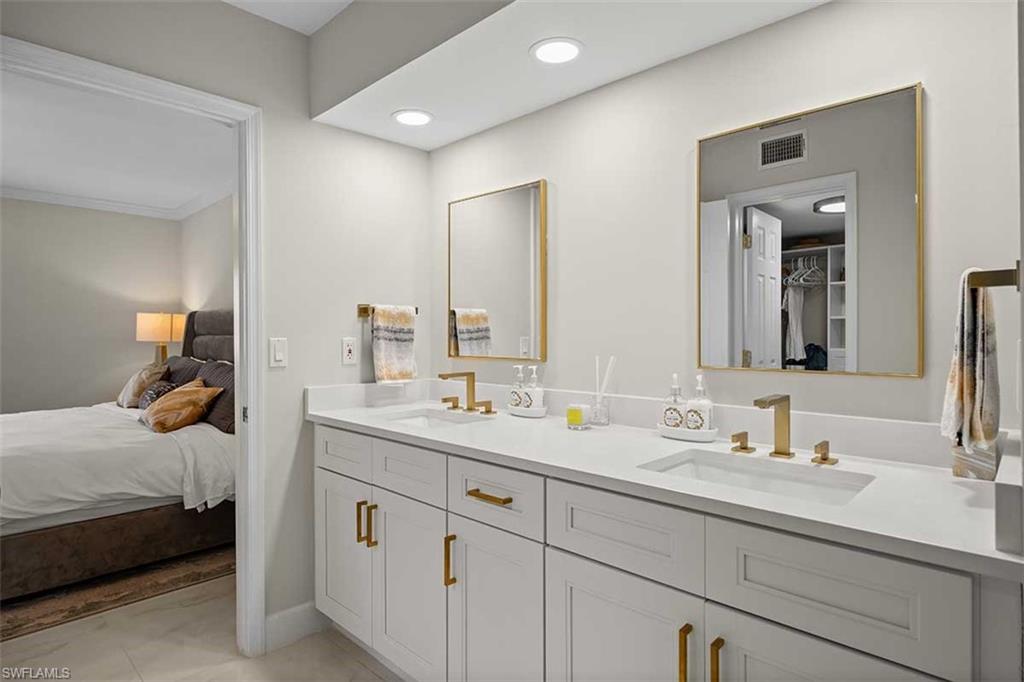 Dual vanity featuring a white countertop with integrated sinks, gold-finish hardware, and framed mirrors