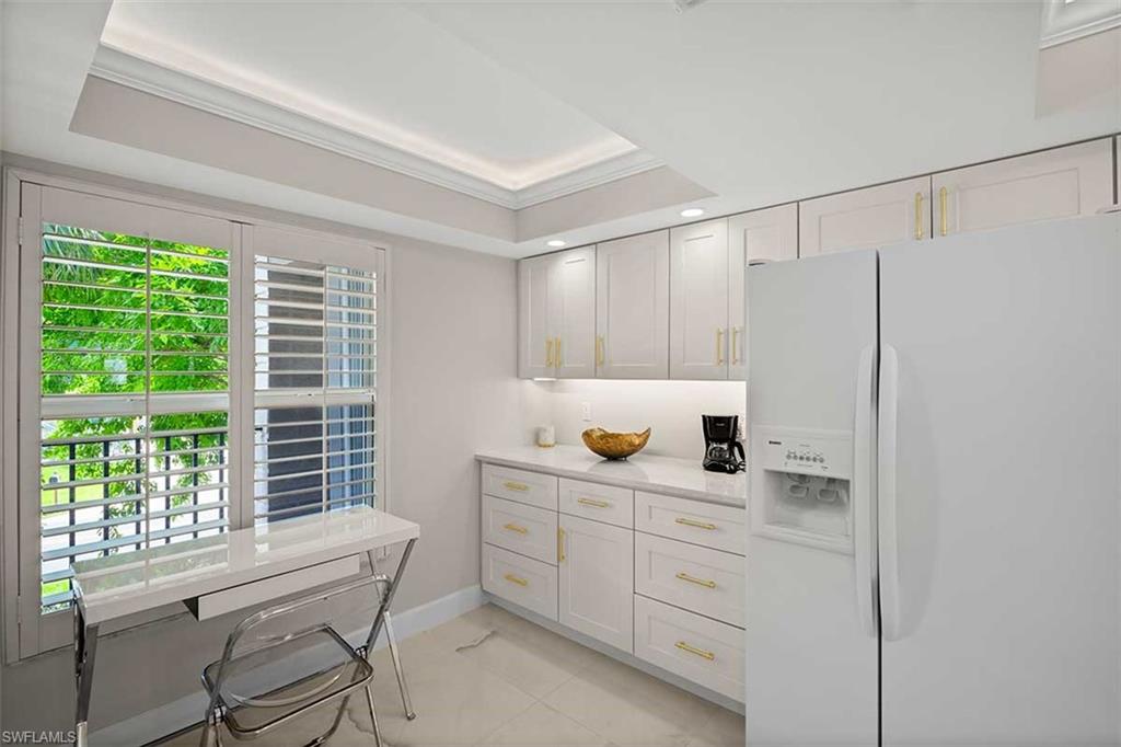 Kitchenette featuring custom cabinetry with gold-tone hardware, a white countertop, recessed lighting, and a tray ceiling