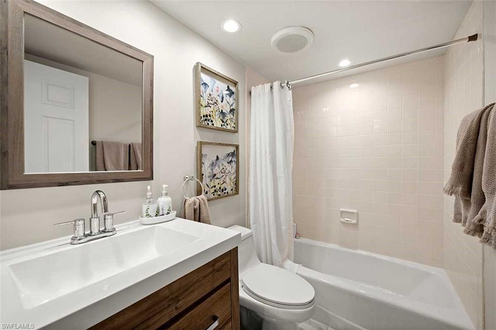 Bathroom featuring a wood-finish vanity with an integrated white sink and chrome faucet