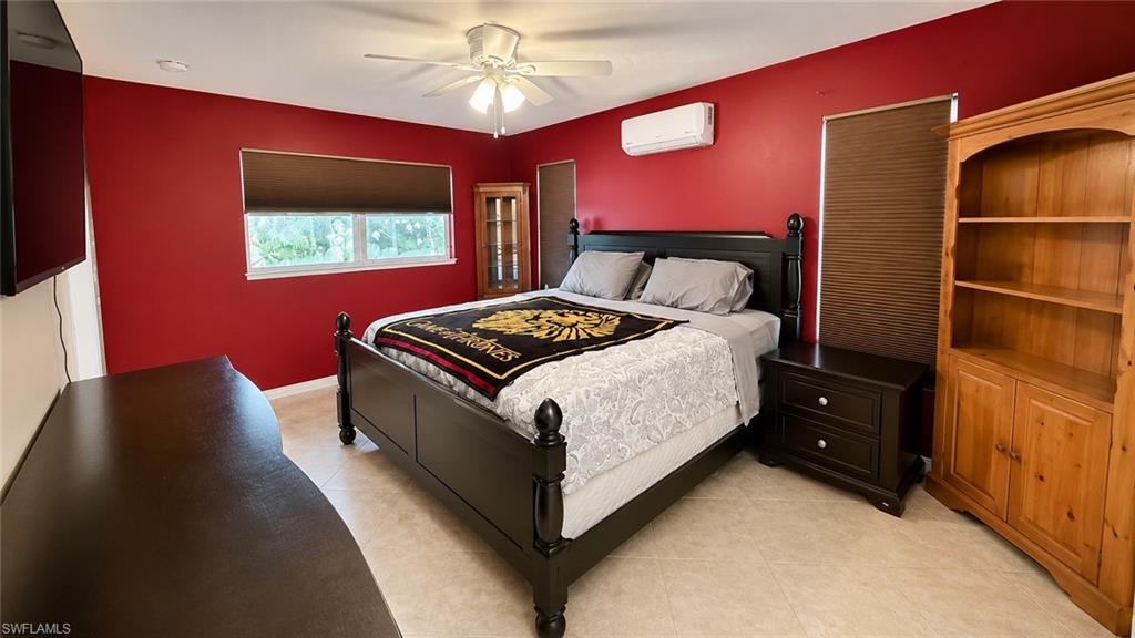 Room featuring a ceiling fan with integrated lighting, a window with a roller blind, and an additional wall-mounted air conditioning unit