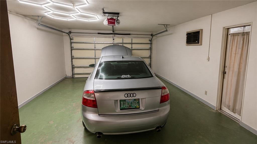 Attached single-car garage featuring a sectional garage door, overhead garage door opener, and a side entry door