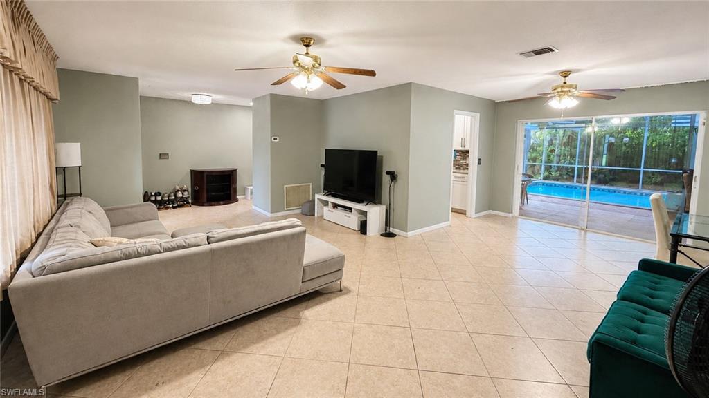 Expansive interior living area featuring neutral wall tones, tile flooring, and two ceiling fans