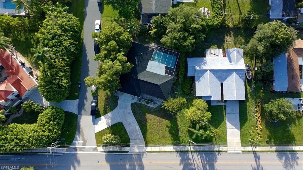 Property featuring a private swimming pool with screened enclosure, mature landscaping, and a concrete driveway