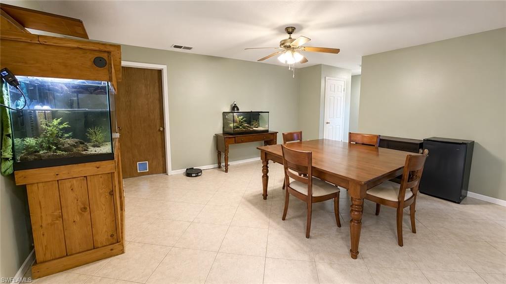 Spacious room featuring light-toned tile flooring, neutral wall paint, and a ceiling fan with integrated lighting