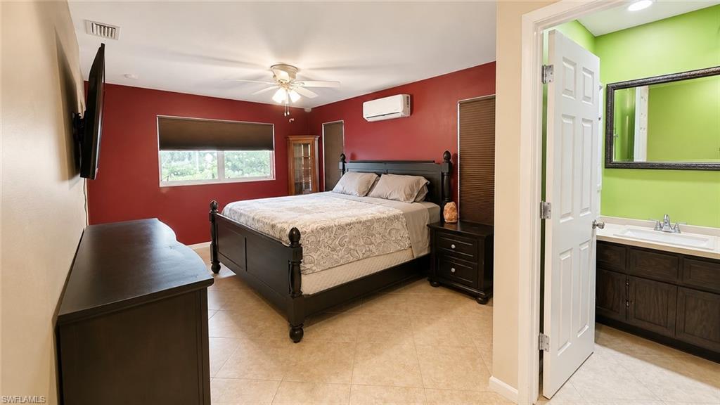 Room featuring tile flooring, a window with roller shade, a ceiling fan, and a wall-mounted air conditioning unit