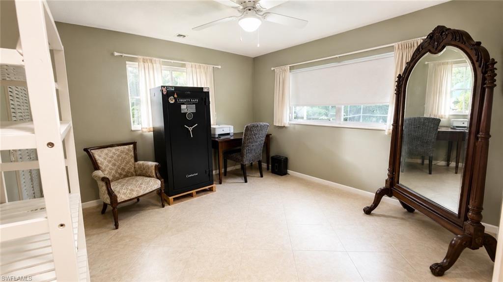 Spacious room featuring light-toned flooring, two windows, and a ceiling fan