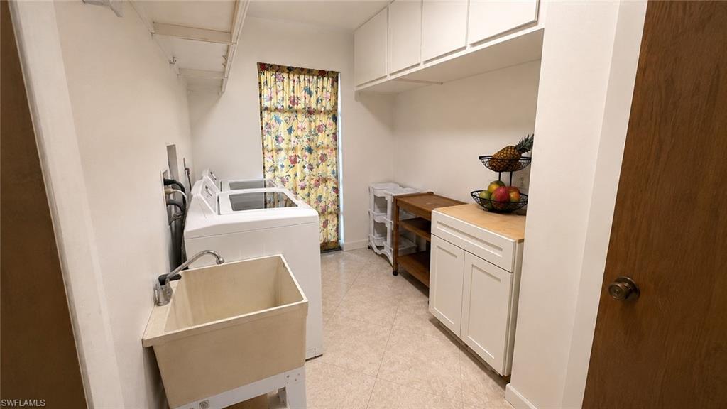 Dedicated laundry area featuring a utility sink with a chrome faucet, overhead cabinetry, and white base cabinets with a wood-finish countertop