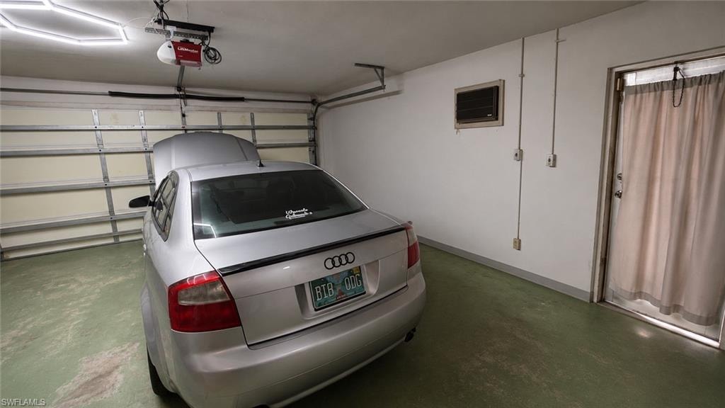 Attached garage featuring an automatic overhead door opener, concrete flooring, a side entry door, and wall-mounted electrical outlets