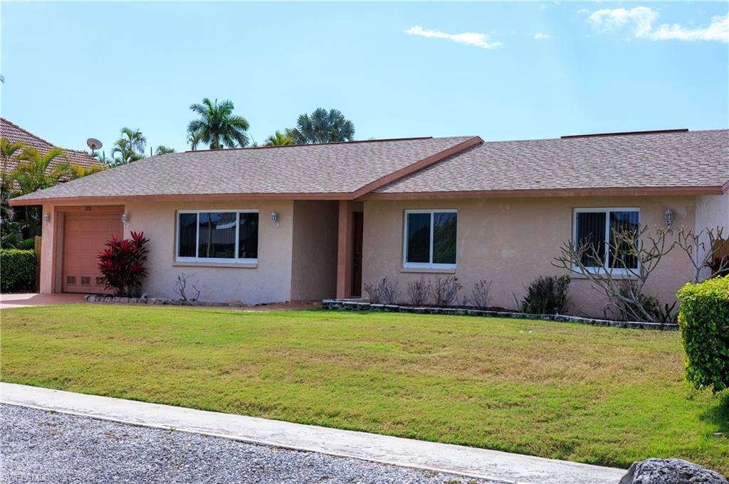 Ranch-style house with stucco siding, a garage, a front yard, and roof with shingles