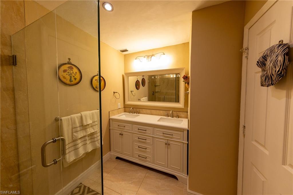 Full bath featuring a shower stall, double vanity, light tile patterned floors, and recessed lighting