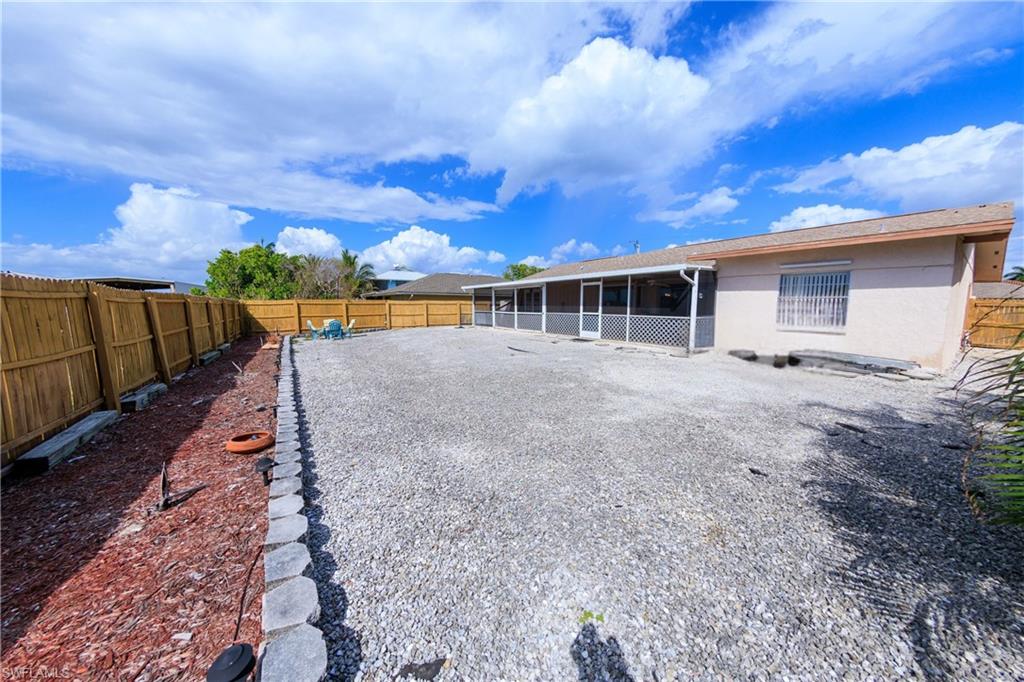 Rear view of house featuring a fenced backyard, a sunroom, and stucco siding