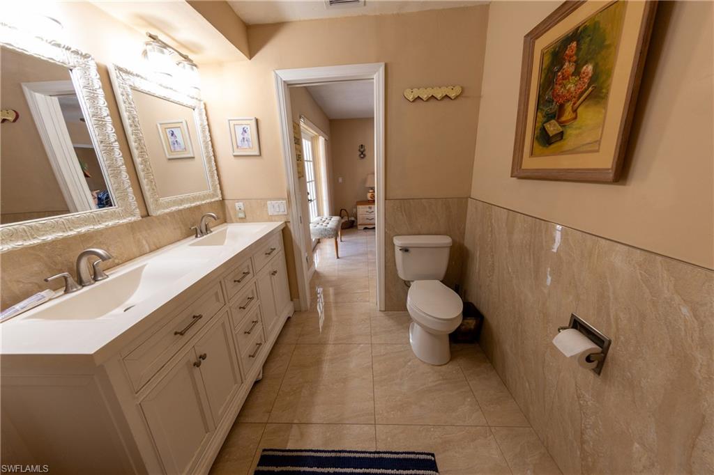 Bathroom with double vanity, tile walls, and a wainscoted wall