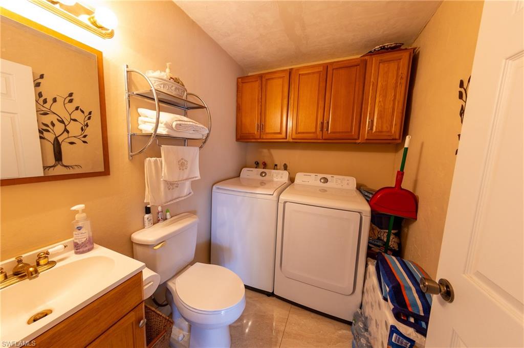 Half bathroom with vanity, washing machine and dryer, and light tile patterned floors