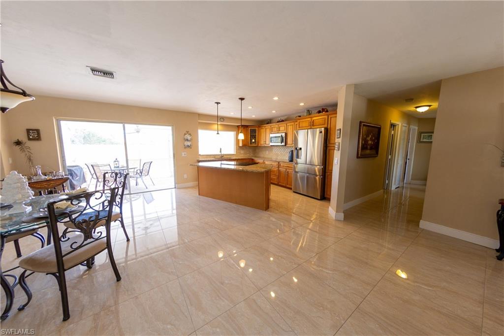 Kitchen with stainless steel appliances, glass insert cabinets, a center island, hanging light fixtures, and wood finish cabinetry