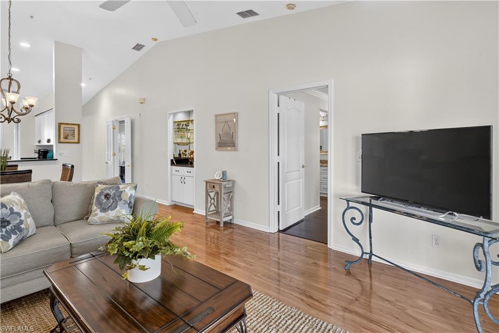 Vaulted ceiling, recessed lighting, wood-finish flooring, built-in bar cabinet, and white interior doors