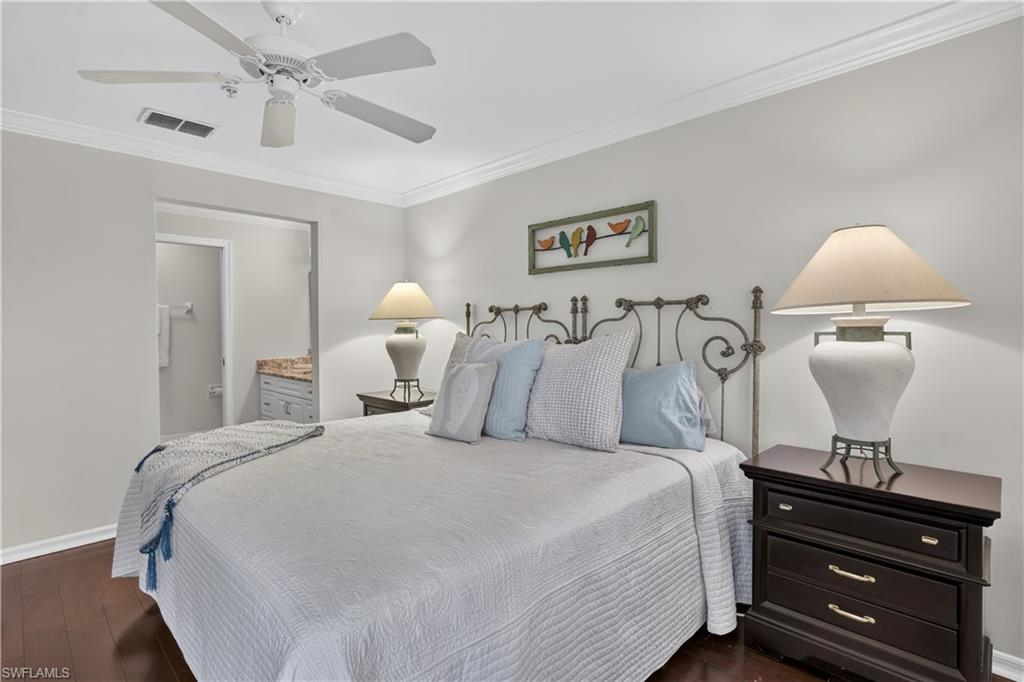 Dark wood-finish flooring, crown molding, and a ceiling fan with integrated lighting
