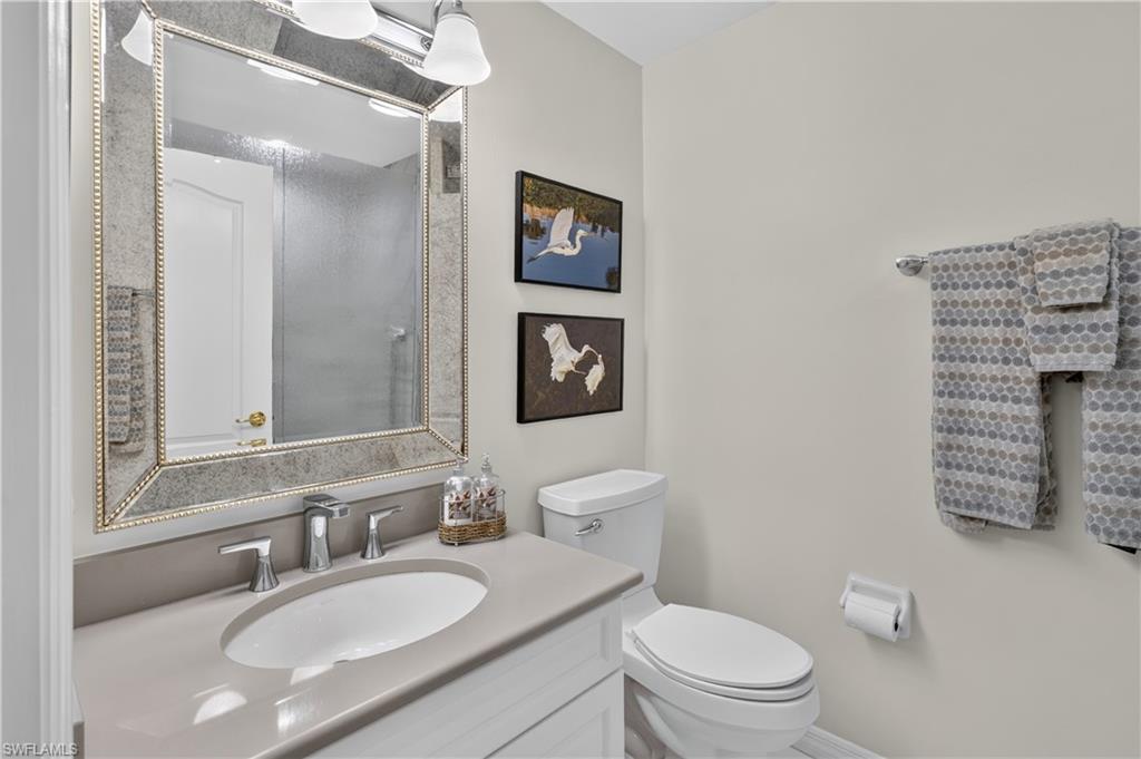 Single vanity with integrated sink, polished chrome faucet, framed mirror, and white toilet