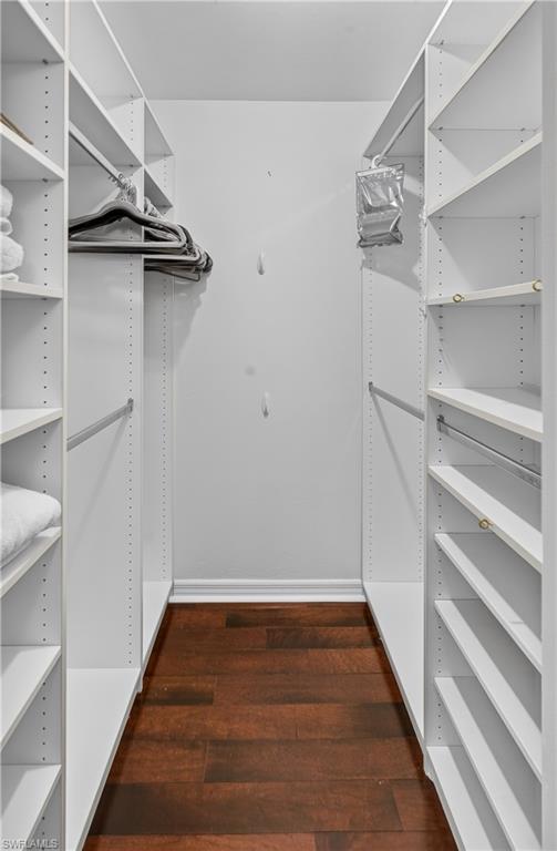 Walk-in closet featuring white shelving units, adjustable shelves, and wood-finish flooring