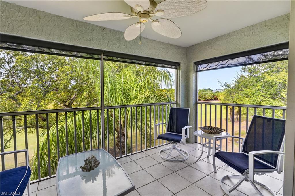 Screened outdoor living area featuring tiled flooring, a ceiling fan, and metal railings