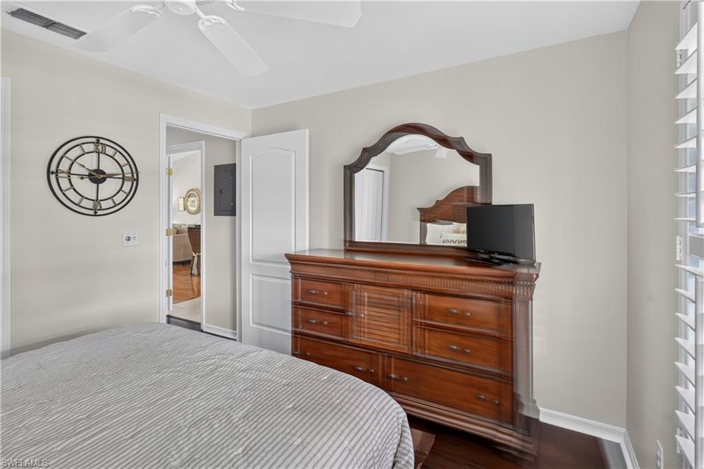 Wood-finish flooring with white baseboards, ceiling fan with light, and interior plantation shutters