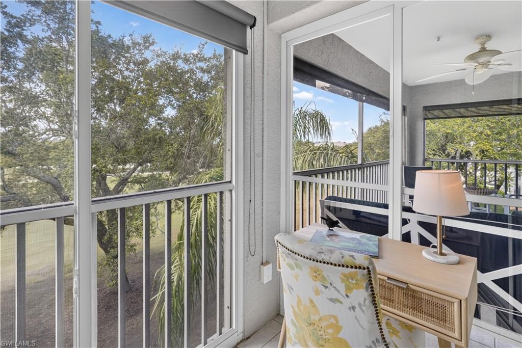 Screened-in balcony with white railings, a ceiling fan, and roll-down shades