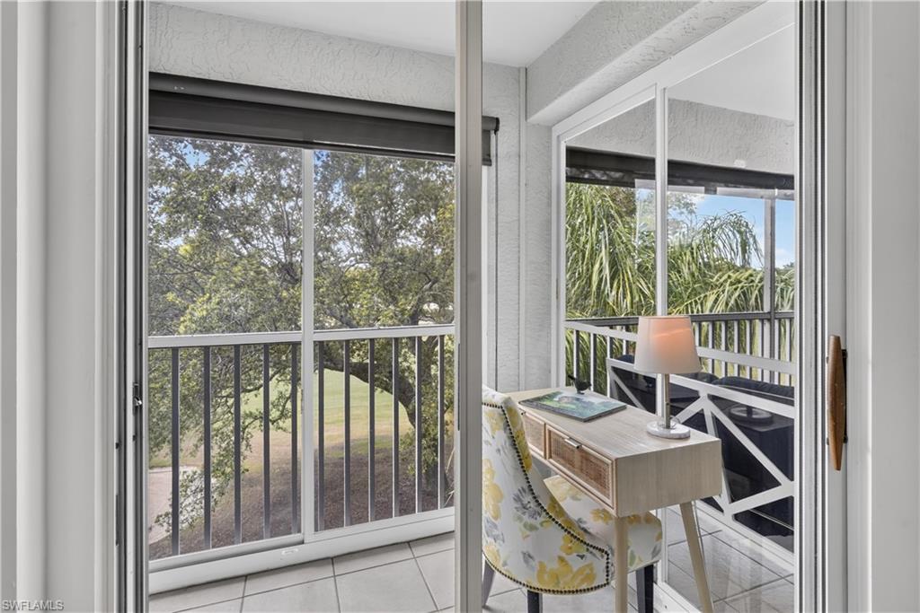 Screened balcony with tile flooring and a dark metal railing