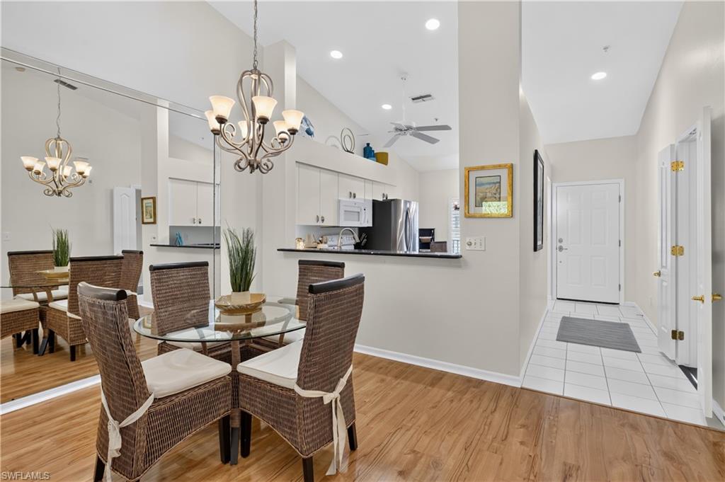 Wood-finish flooring, mirrored wall, vaulted ceiling, recessed lighting, and a prominent chandelier