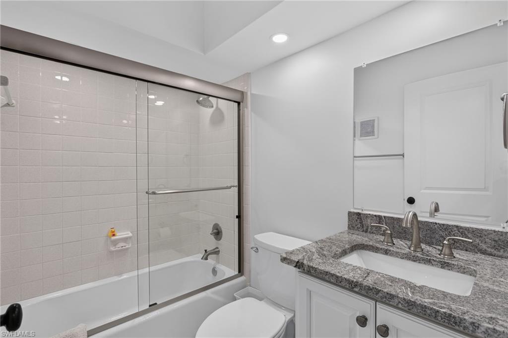 Guest bathroom with new tile, heavy glass doors, vanity, lighting/plumbing fixtures.