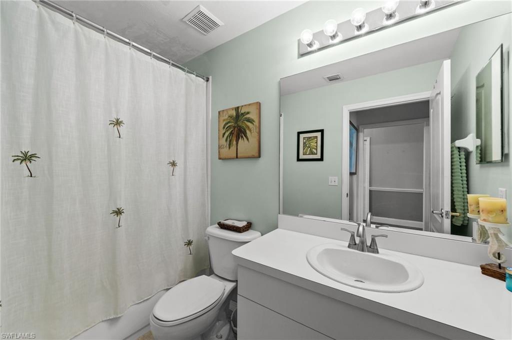 Bathroom featuring a vanity with an integrated sink, a large wall-mounted mirror, and a wall-mounted light fixture
