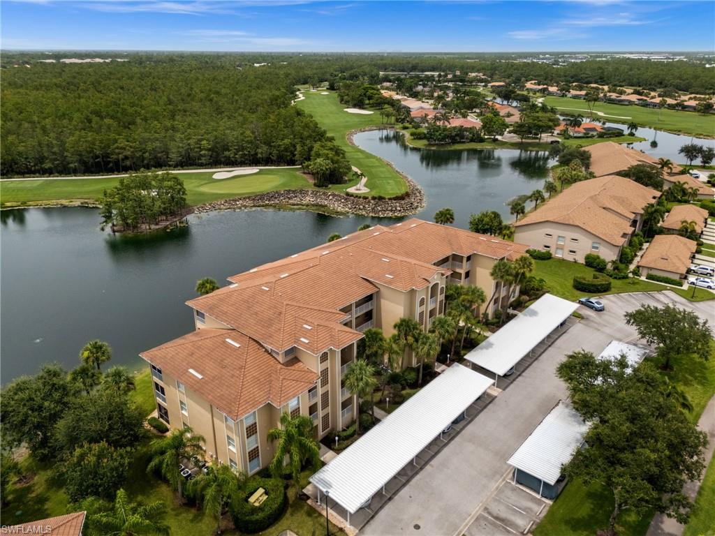 Multi-story residential building with tile roofing, surrounded by lush landscaping and mature palm trees