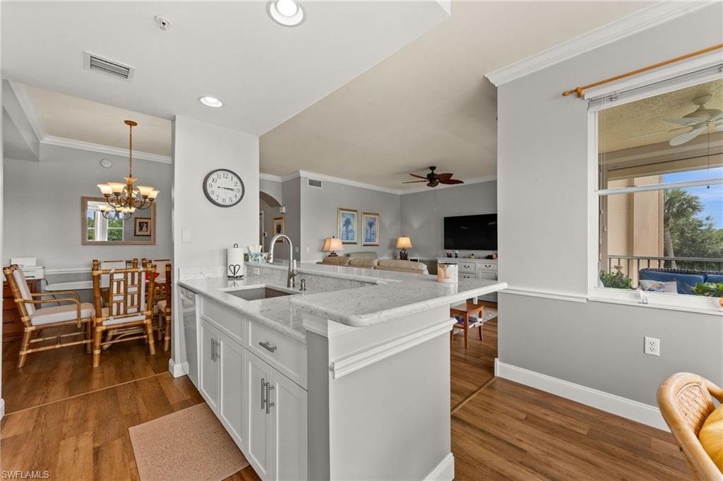 Open-concept kitchen featuring white cabinetry, light-toned countertops, and a stainless steel sink with a gooseneck faucet