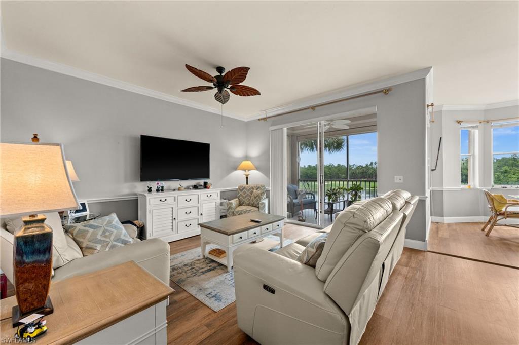 Living area featuring wood-finish flooring, crown molding, and a ceiling fan with leaf-shaped blades