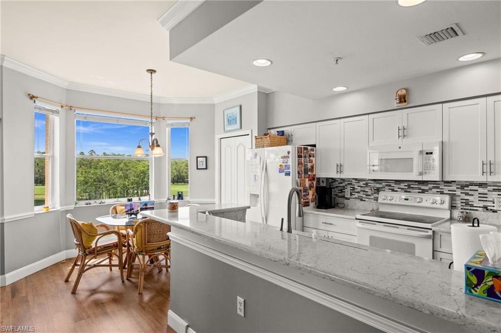 Kitchen featuring white cabinetry, light-toned countertops, tile backsplash, and wood-finish flooring