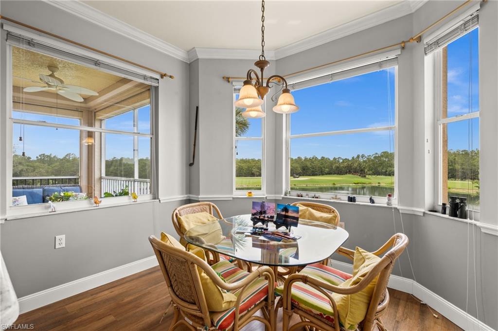 Dining area featuring wood-finish flooring, a contemporary chandelier, and a bay window configuration