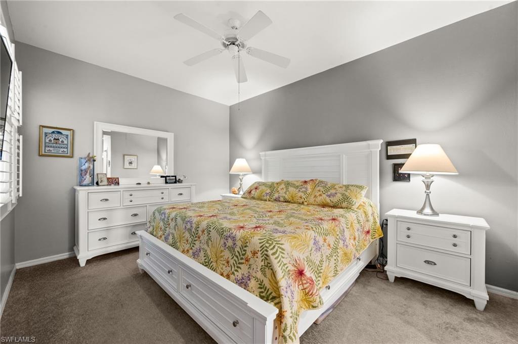 Bedroom featuring a vaulted ceiling with a ceiling fan, white plantation shutters, and soft gray wall paint