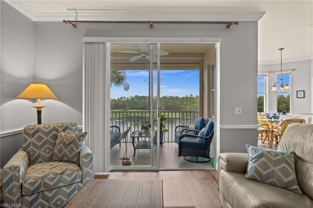 Sliding glass doors open to a screened balcony overlooking a tranquil water feature and mature foliage