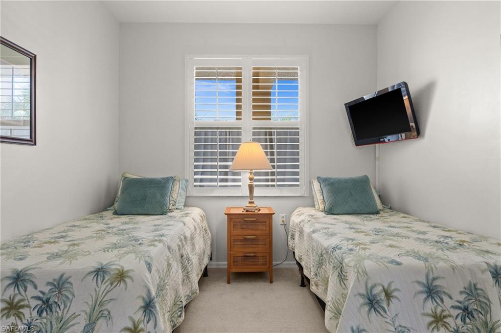 Twin beds flanking a central window with white plantation shutters