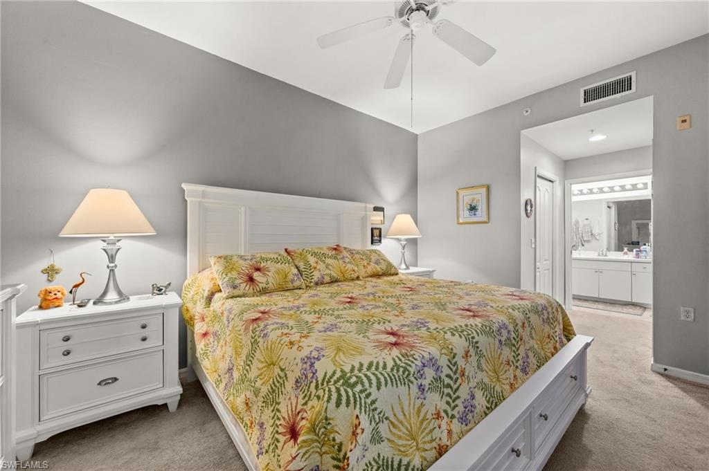 Bedroom featuring a white paneled bed frame and headboard, ceiling fan, and carpeted flooring