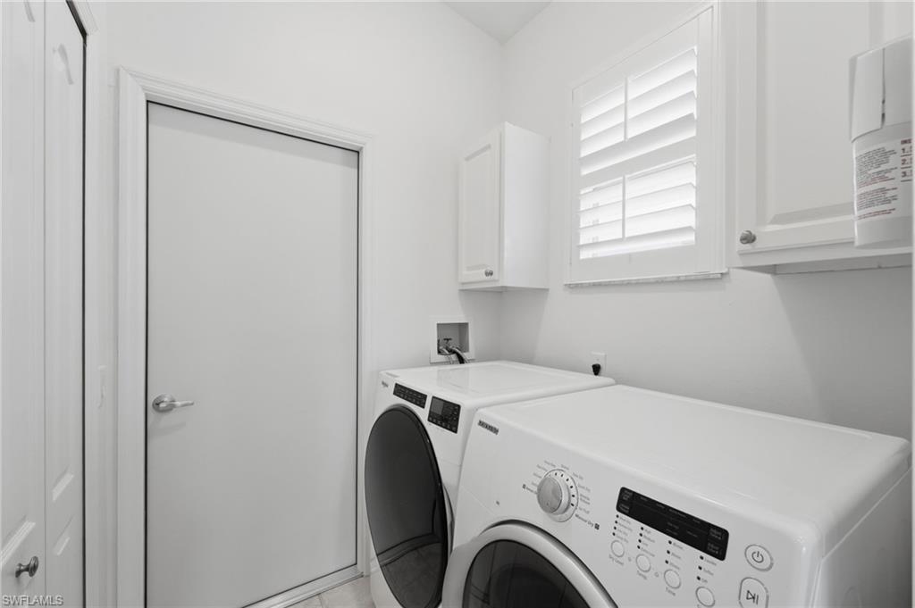 The well-appointed laundry room offers exceptional functionality with a spacious storage closet, additional cabinetry above the washer and dryer for added organization, and a window that fills the space with natural light.