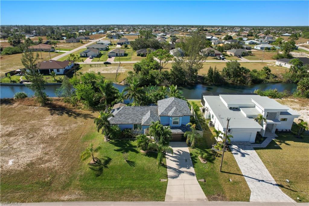 Canal-front property featuring a two-story residence with a multi-gabled roof and a well-maintained lawn