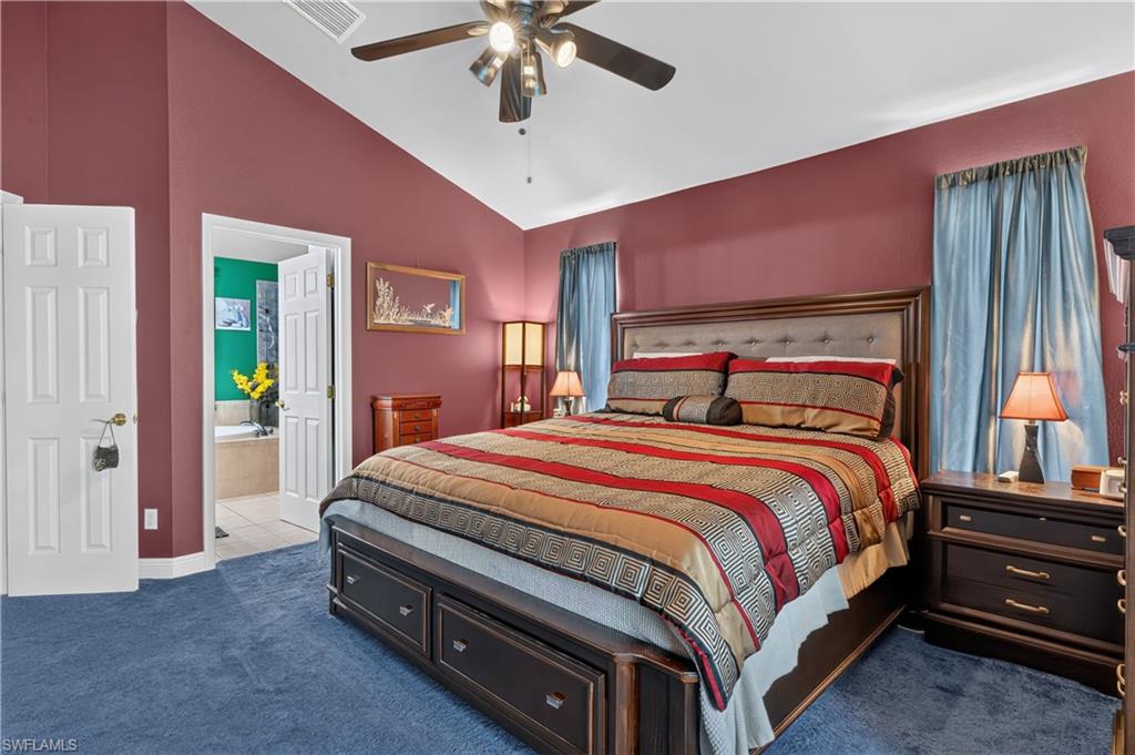 Spacious bedroom featuring vaulted ceilings, a ceiling fan with integrated lighting, and plush blue carpeting