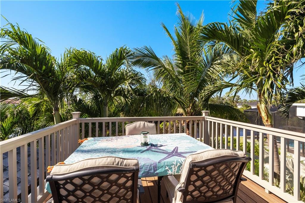 Upper-level deck featuring composite wood-finish flooring, white railing, and mature palm trees