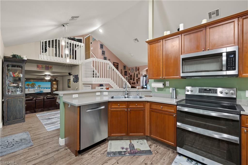 Kitchen featuring wood-finish flooring, warm-toned cabinetry, stainless steel appliances, and light-toned countertops