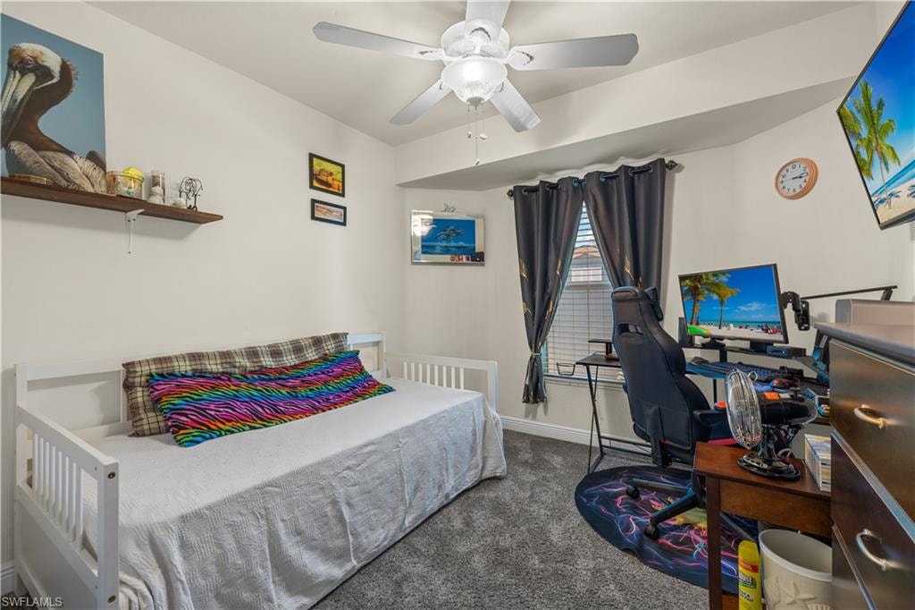 Carpeted room featuring a ceiling fan with integrated lighting, a window with blinds and dark curtains, and a built-in shelving nook