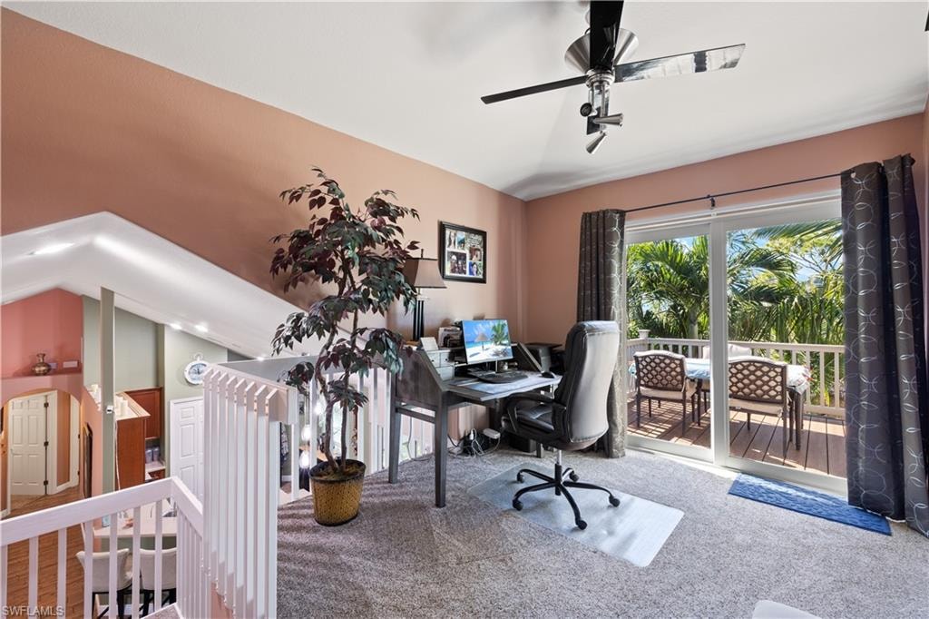 Carpeted loft space with a ceiling fan, offering direct access to an outdoor deck through sliding glass doors