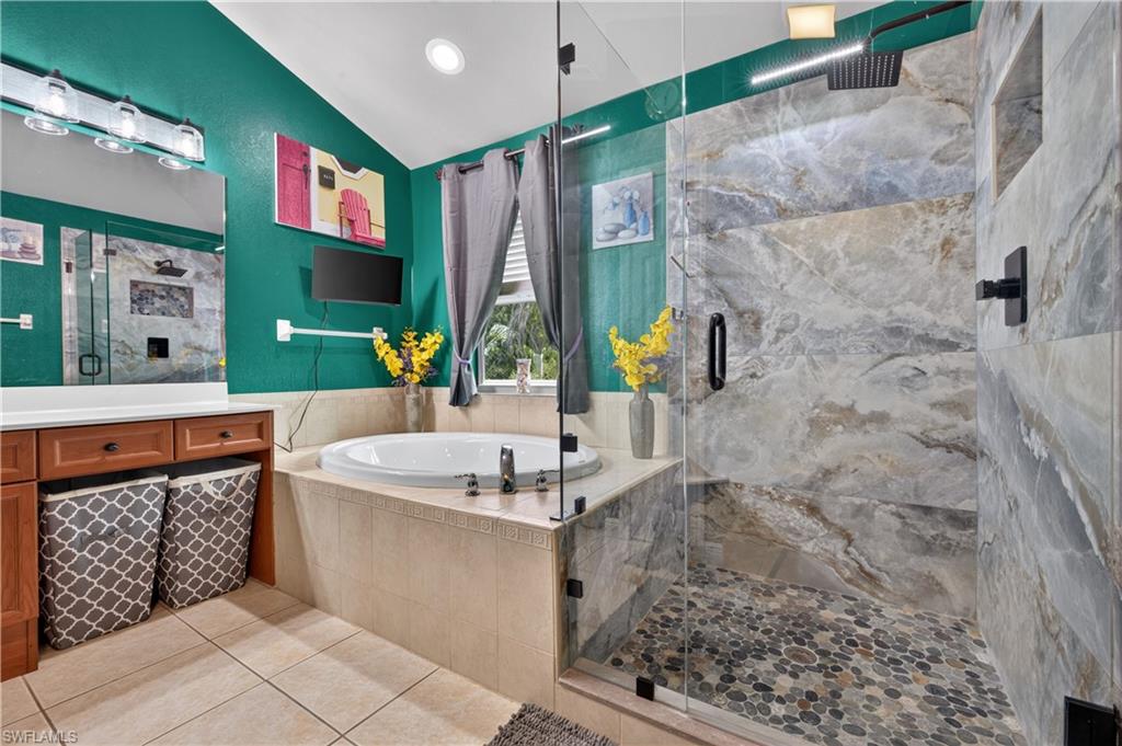 Bathroom featuring a spacious walk-in shower with a glass enclosure, large format stone-finish tile, and a pebble-stone floor