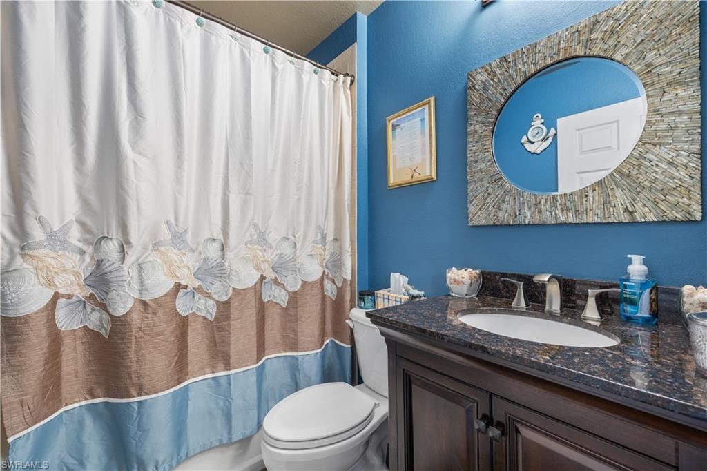 Bathroom with dark wood-finish vanity, granite countertop, undermount sink, and brushed nickel faucet